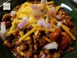 Bowl of simple beef chili topped with sour cream, ages cheddar and shallots.