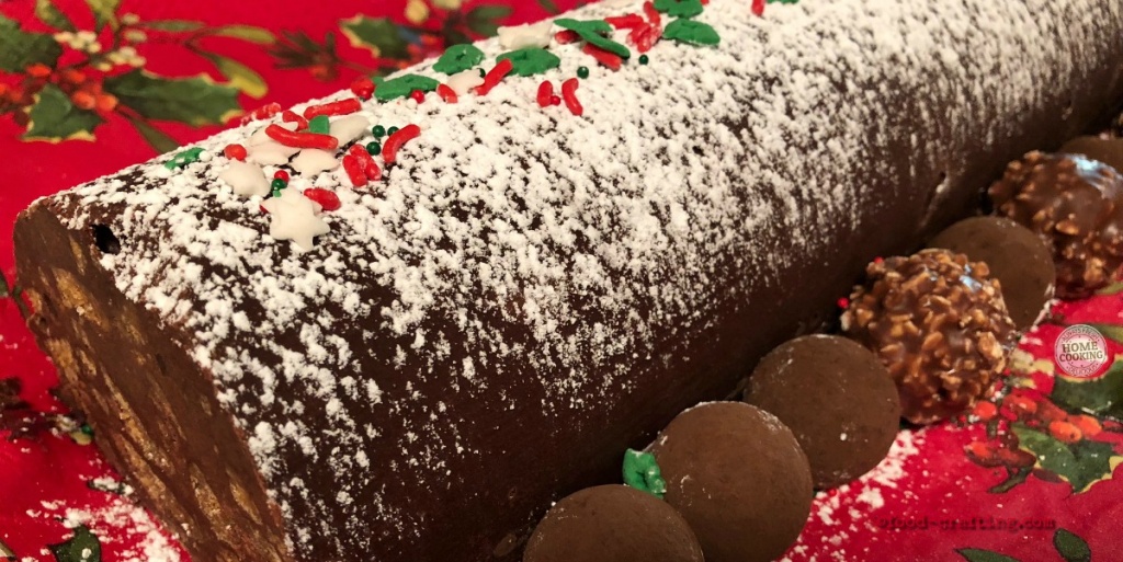 easy-christmas-yule-log topped with powdered sugar and holly shaped candy bits plu ssprinkled