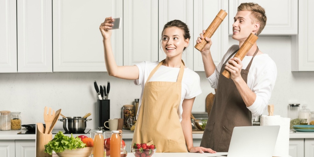 Young woman and man wearing kitchen aprons with pockets